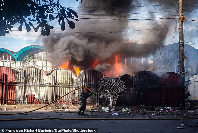 A firefighter tries to extinguish the fire at the central market in Sumy, Ukraine, caused by the explosion of a Russian drone, in Sumy, Ukraine, on Friday