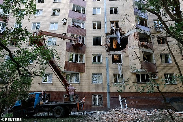 Workers remove debris in a block of flats damaged by overnight shelling in Donetsk, a Russian-controlled city of Ukraine, on Saturday morning