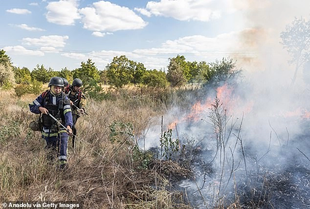 Ukrainian firefighters extinguish a fire in a municipal park following a Russian artillery attack on the city of Kostiantynivka, Ukraine on Friday