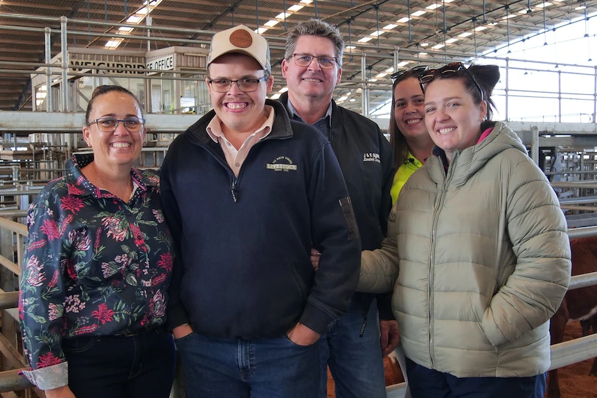 Five people at saleyards looking at camera smiling