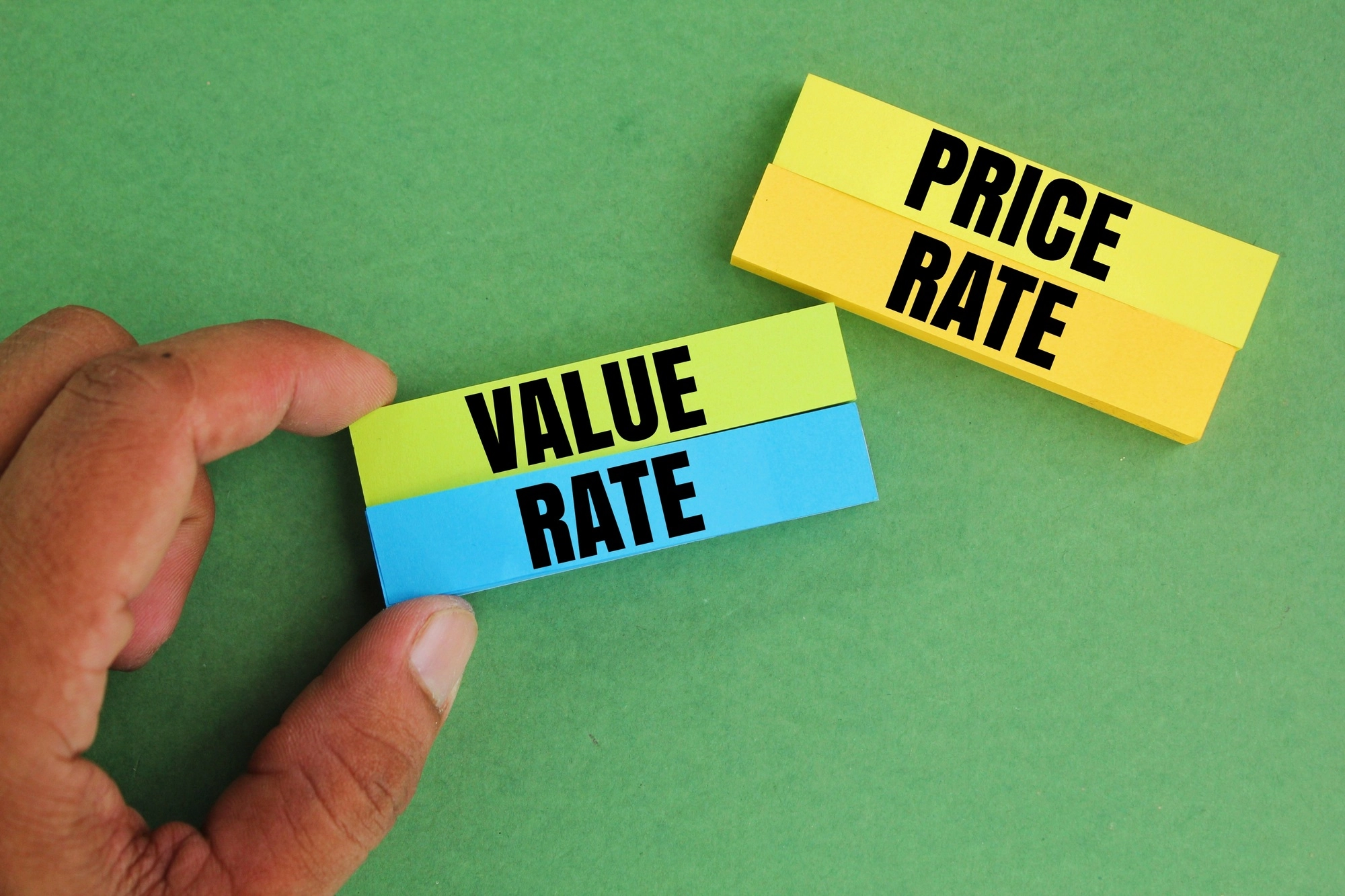 hand holding colored paper with the words value rate and price rate.
